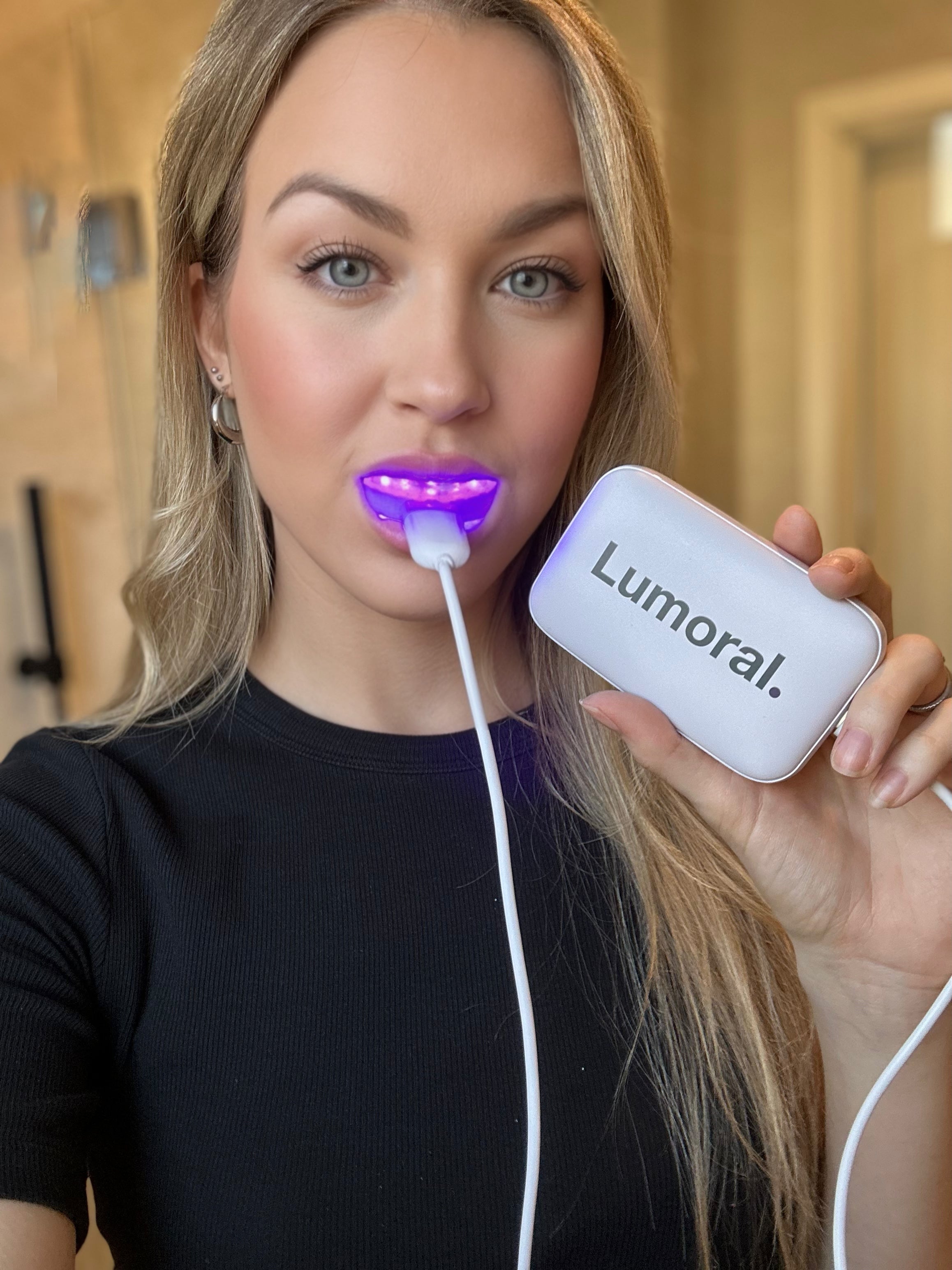 Jonge vrouw gebruikt Lumoral mondstuk en houdt de externe batterij in haar hand