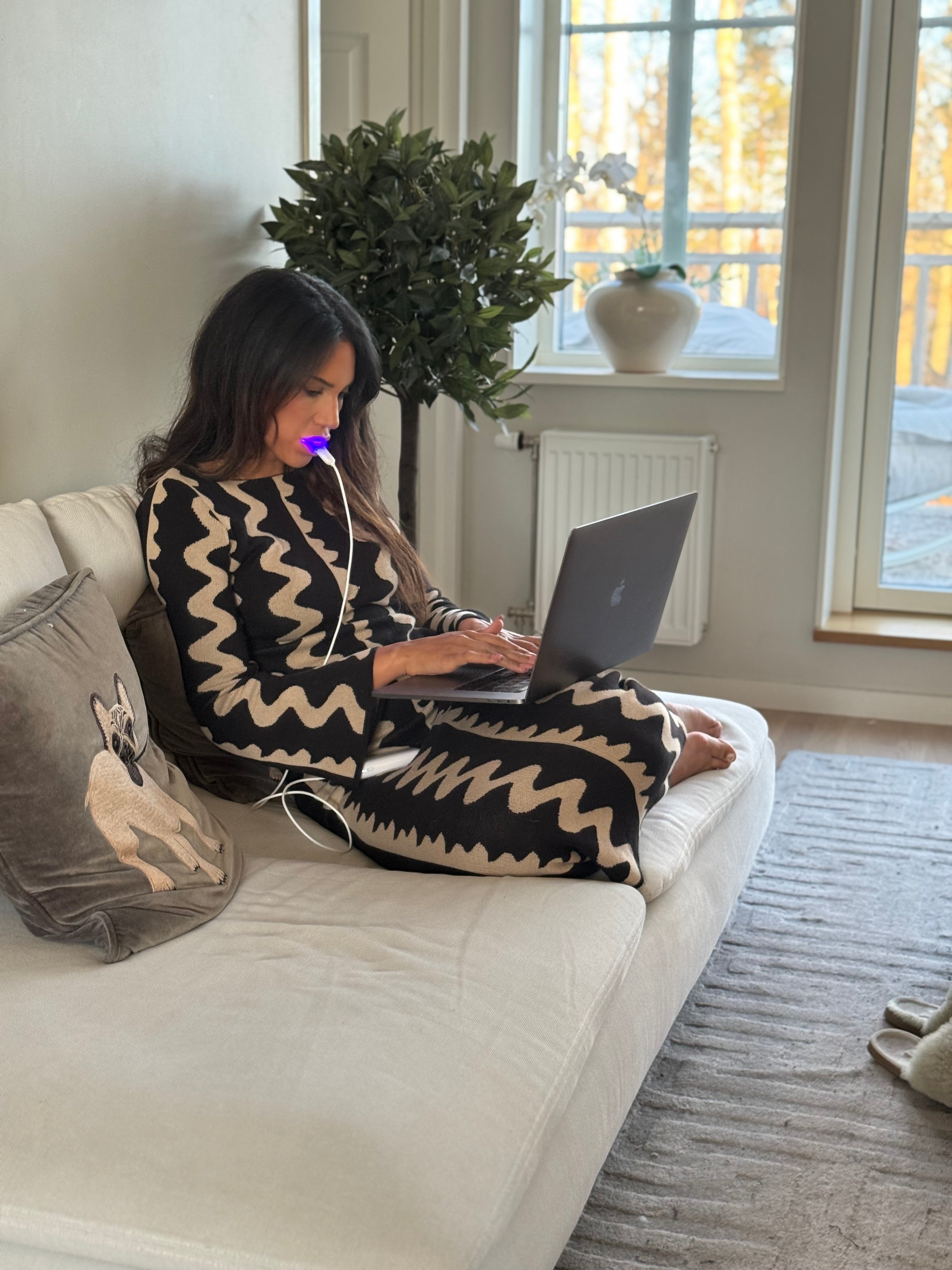 Jonge vrouw werkt op laptop in zetel terwijl ze het Lumoral mondstuk gebruikt