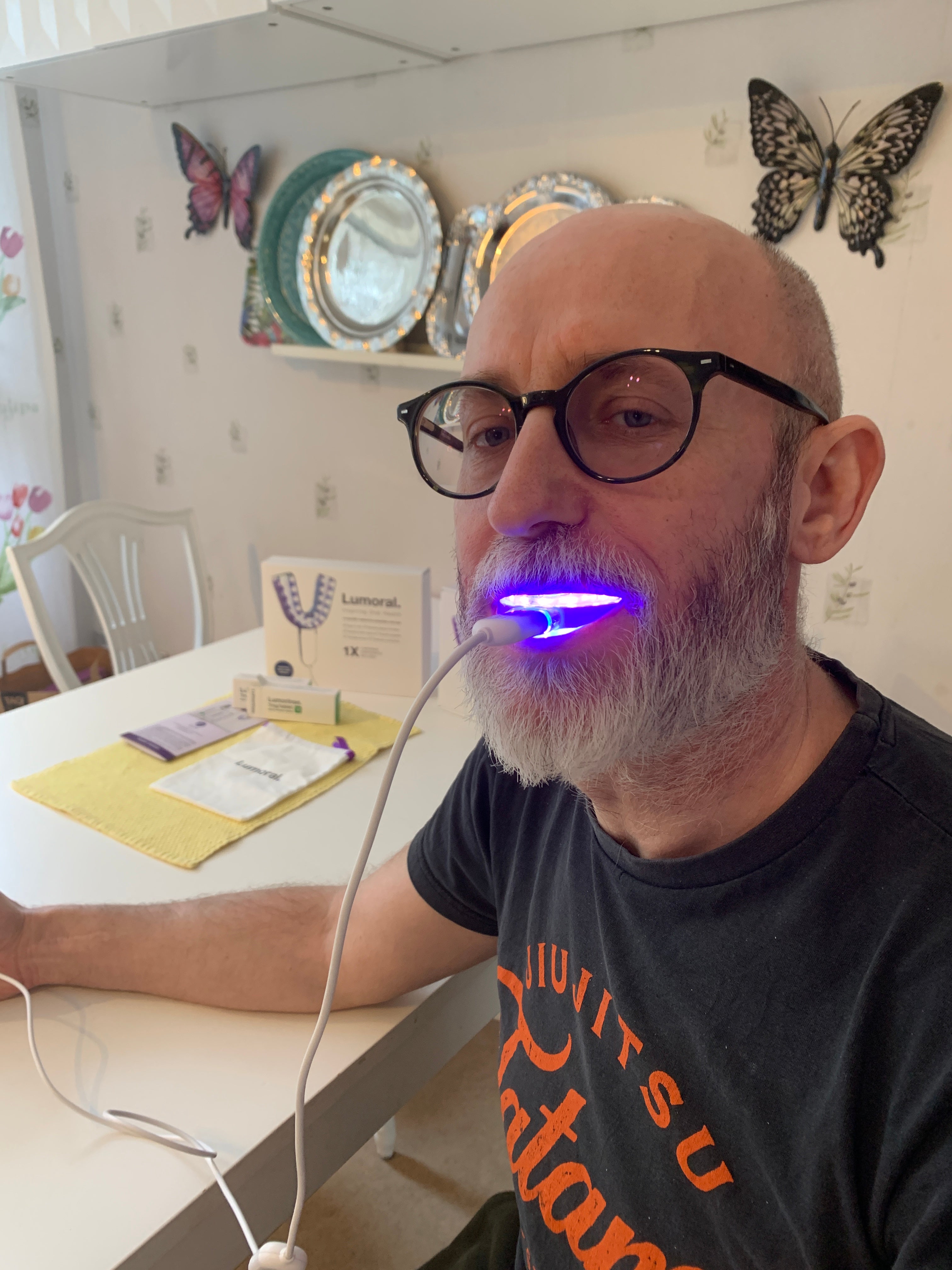 Een man die het lumoral mondstuk in zijn mond heeft. Het toestel staat aan en geeft licht