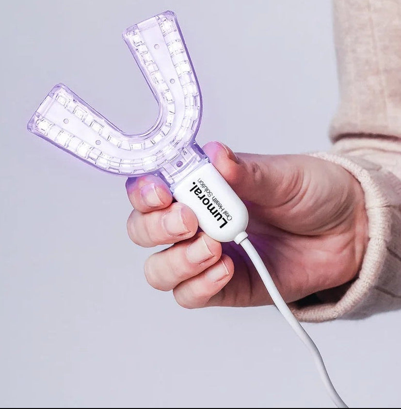 Een close up van het lumoral mondstuk dat iemand vast heeft in haar hand met oplaadkabel erbij